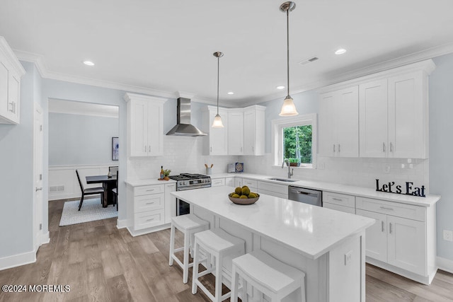 kitchen with wall chimney exhaust hood, stainless steel appliances, sink, white cabinetry, and light hardwood / wood-style floors