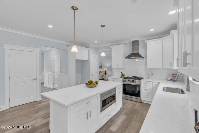 kitchen with white cabinetry, stainless steel appliances, wall chimney exhaust hood, and decorative light fixtures