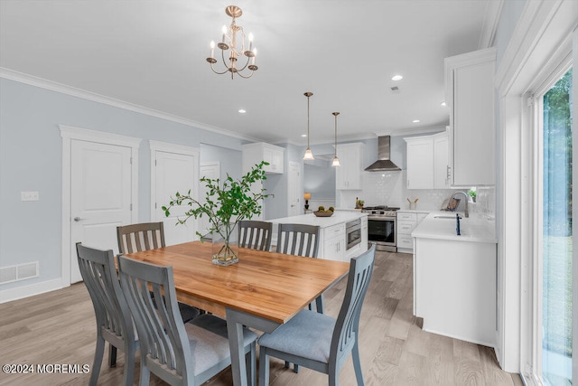 dining area with ornamental molding, sink, a notable chandelier, and light hardwood / wood-style floors