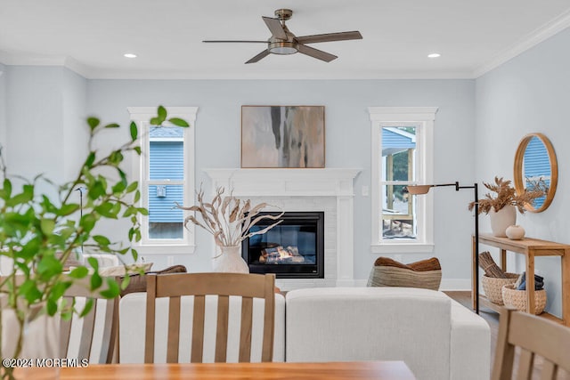 living room with a high end fireplace, crown molding, and ceiling fan