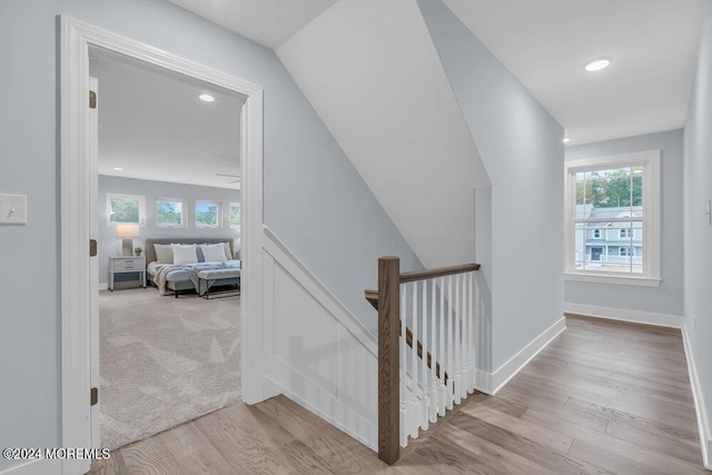 staircase with a wealth of natural light, hardwood / wood-style floors, and vaulted ceiling