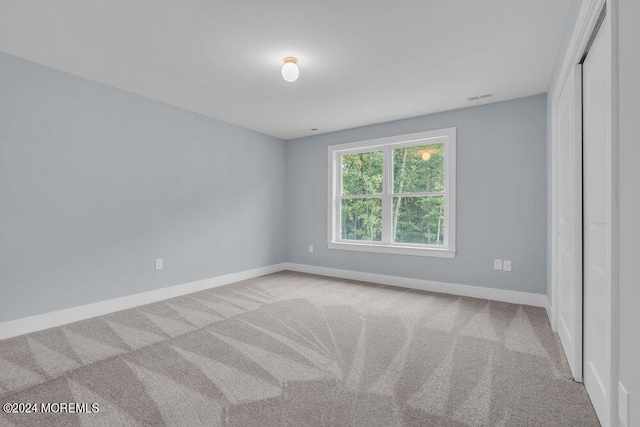 unfurnished bedroom with a closet and light colored carpet