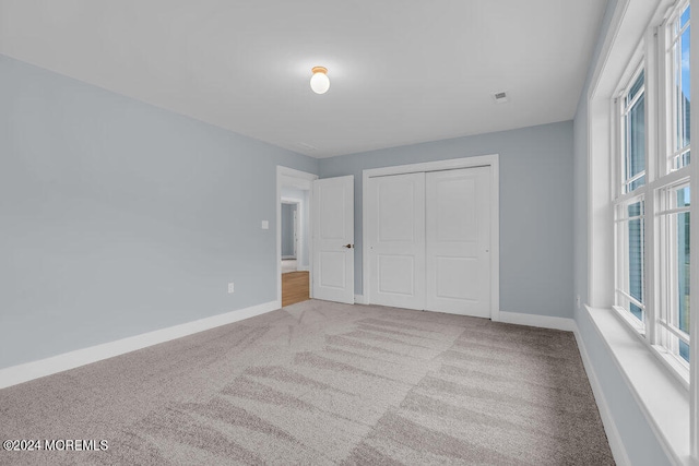 unfurnished bedroom featuring a closet and light colored carpet