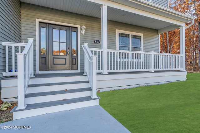 doorway to property with a porch and a lawn