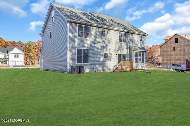 rear view of house with central air condition unit and a lawn