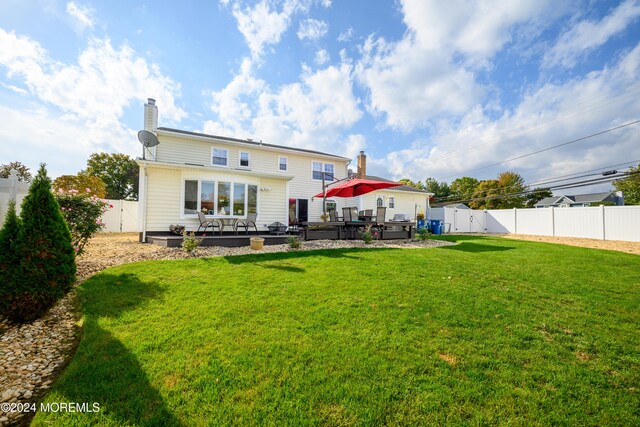 rear view of house featuring a wooden deck and a lawn