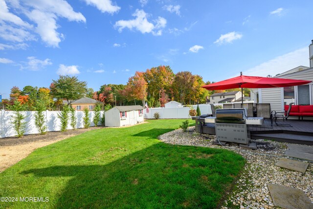 view of yard with an outdoor living space, a shed, and a deck