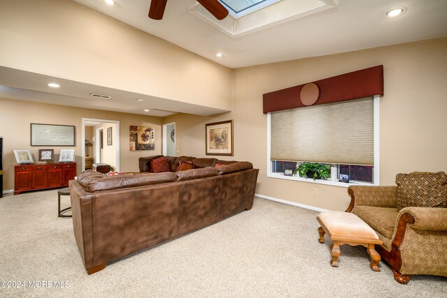 carpeted living room with ceiling fan and a skylight