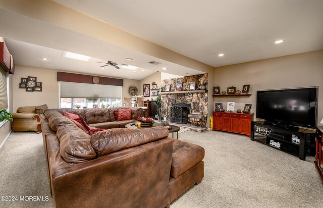 carpeted living room featuring vaulted ceiling, a fireplace, and ceiling fan