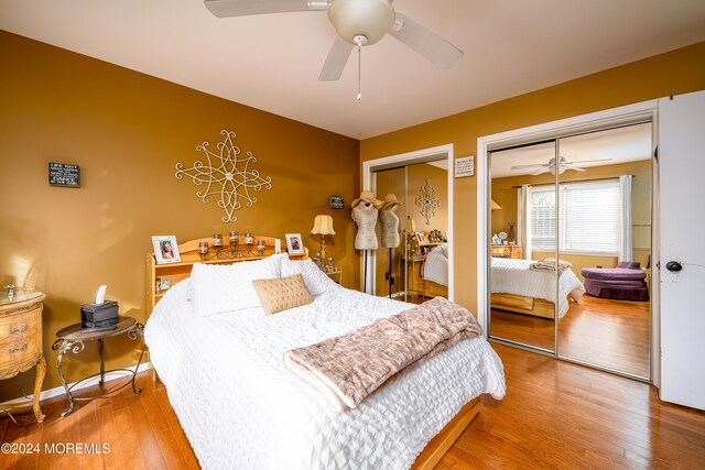 bedroom with multiple closets, hardwood / wood-style flooring, and ceiling fan