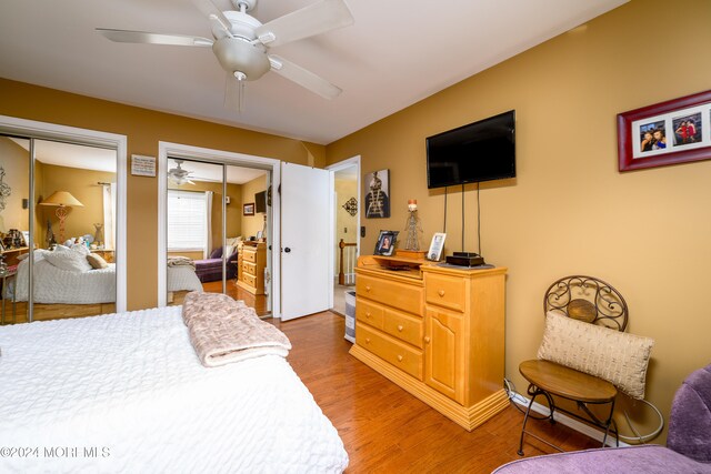 bedroom featuring ceiling fan, multiple closets, and wood-type flooring