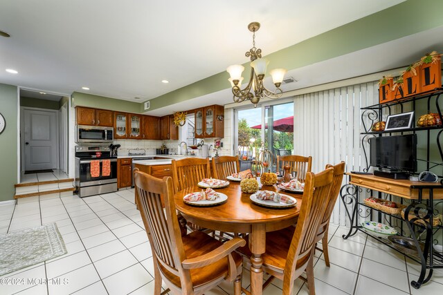 tiled dining room featuring an inviting chandelier and sink