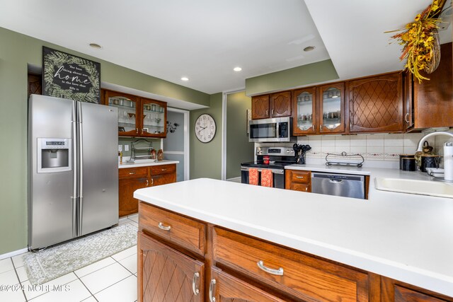 kitchen featuring sink, appliances with stainless steel finishes, backsplash, and light tile patterned floors