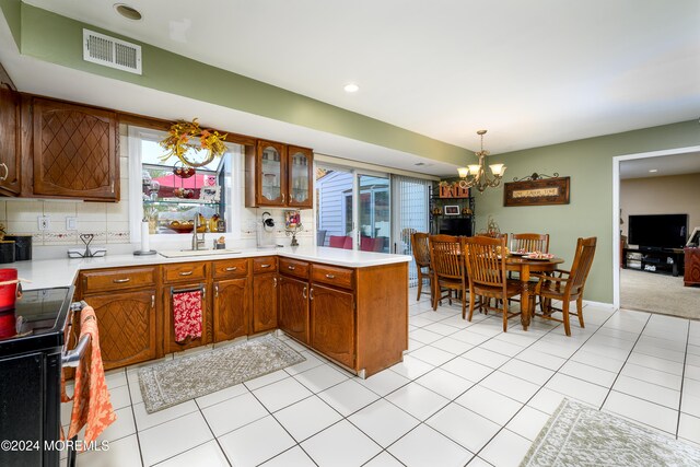 kitchen featuring tasteful backsplash, hanging light fixtures, an inviting chandelier, black / electric stove, and sink