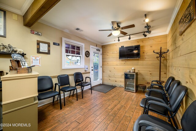 sitting room featuring wood walls, ceiling fan, dark wood-type flooring, ornamental molding, and track lighting