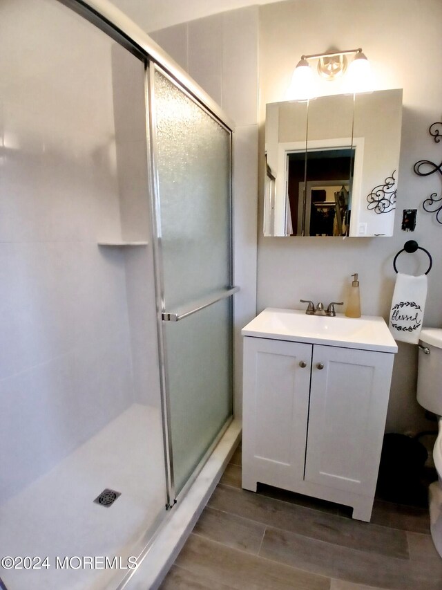 bathroom featuring vanity, toilet, hardwood / wood-style flooring, and walk in shower