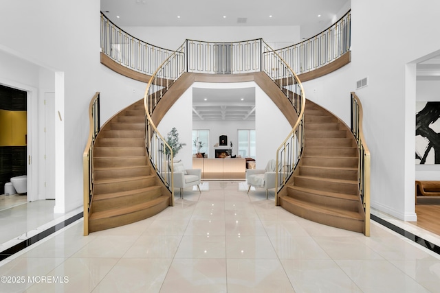 stairs featuring tile patterned floors, a towering ceiling, and coffered ceiling