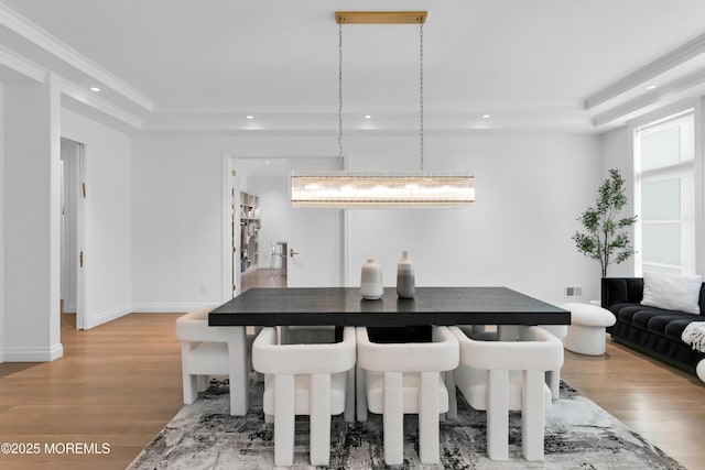 dining space with a chandelier, light wood-type flooring, a tray ceiling, and ornamental molding