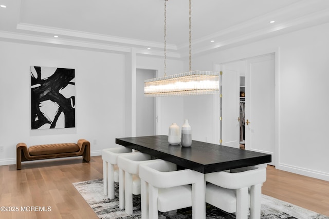 dining room with wood-type flooring, a raised ceiling, a notable chandelier, and crown molding