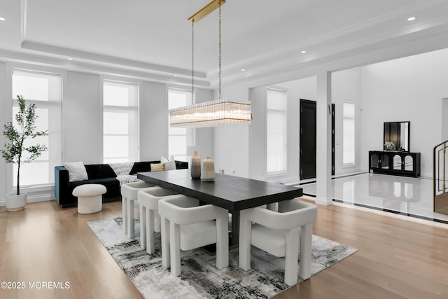 dining area with a chandelier, light wood-type flooring, and a tray ceiling