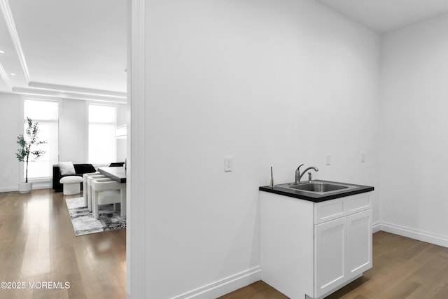 bar with white cabinetry, sink, and wood-type flooring