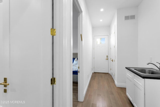 hallway featuring sink and light hardwood / wood-style floors