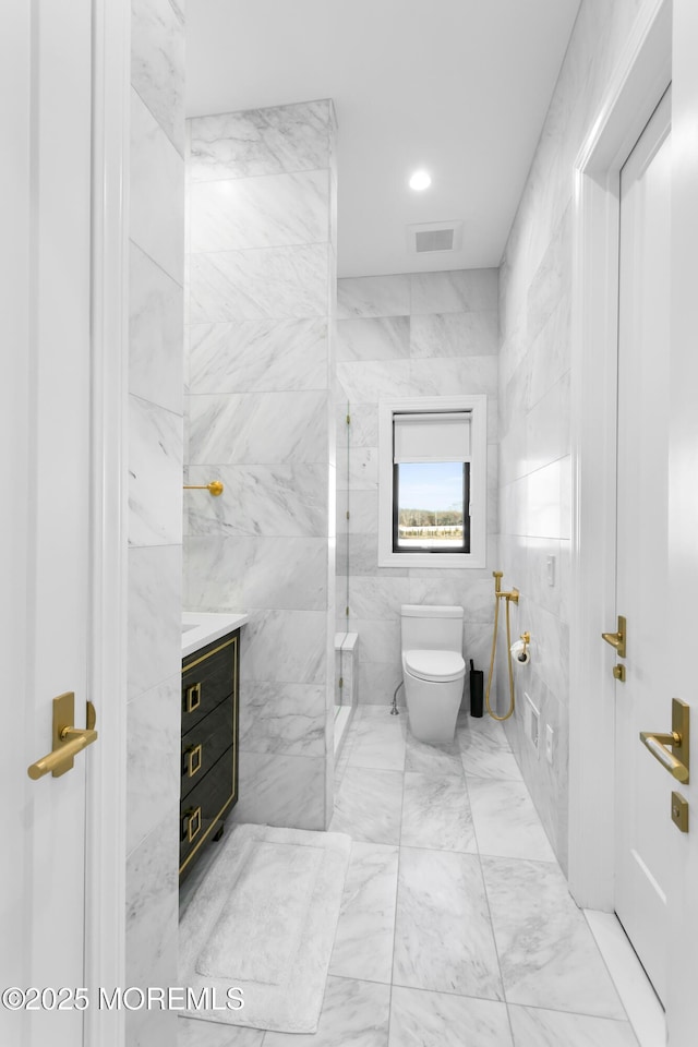 bathroom with walk in shower, vanity, tile walls, and toilet