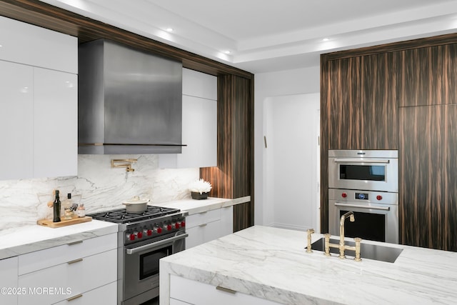 kitchen with light stone counters, dark brown cabinetry, stainless steel appliances, sink, and white cabinetry