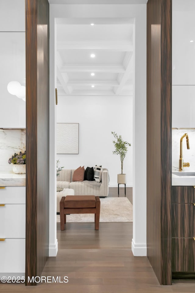 hall featuring hardwood / wood-style floors, beam ceiling, sink, and coffered ceiling