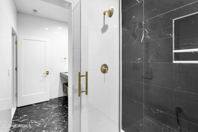 bathroom featuring a shower with door and tile walls