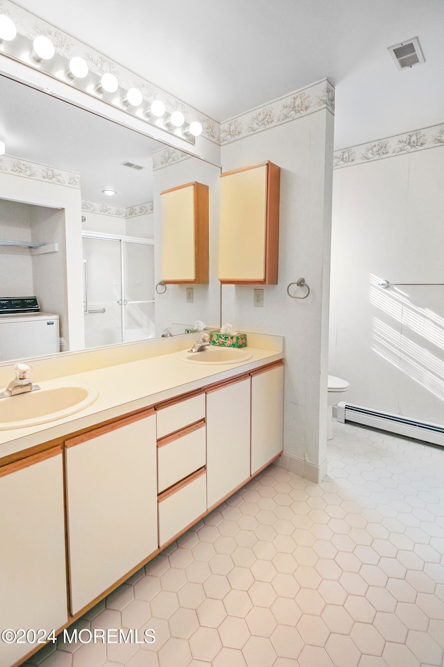 bathroom featuring washer / dryer, a baseboard heating unit, toilet, walk in shower, and vanity