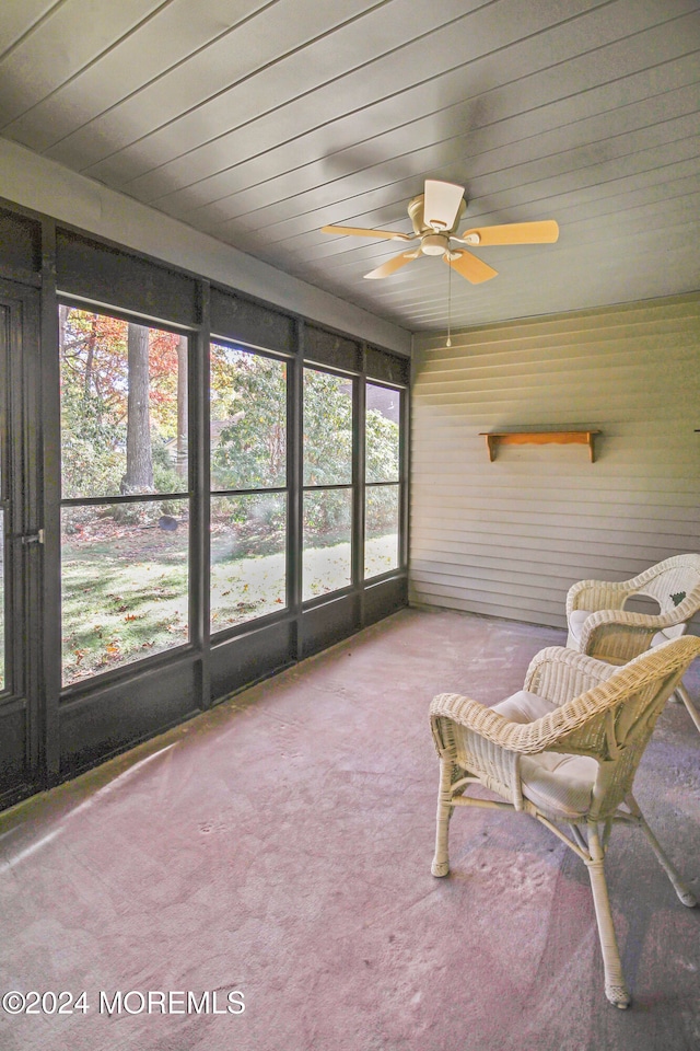 unfurnished sunroom with ceiling fan, a healthy amount of sunlight, and wood ceiling