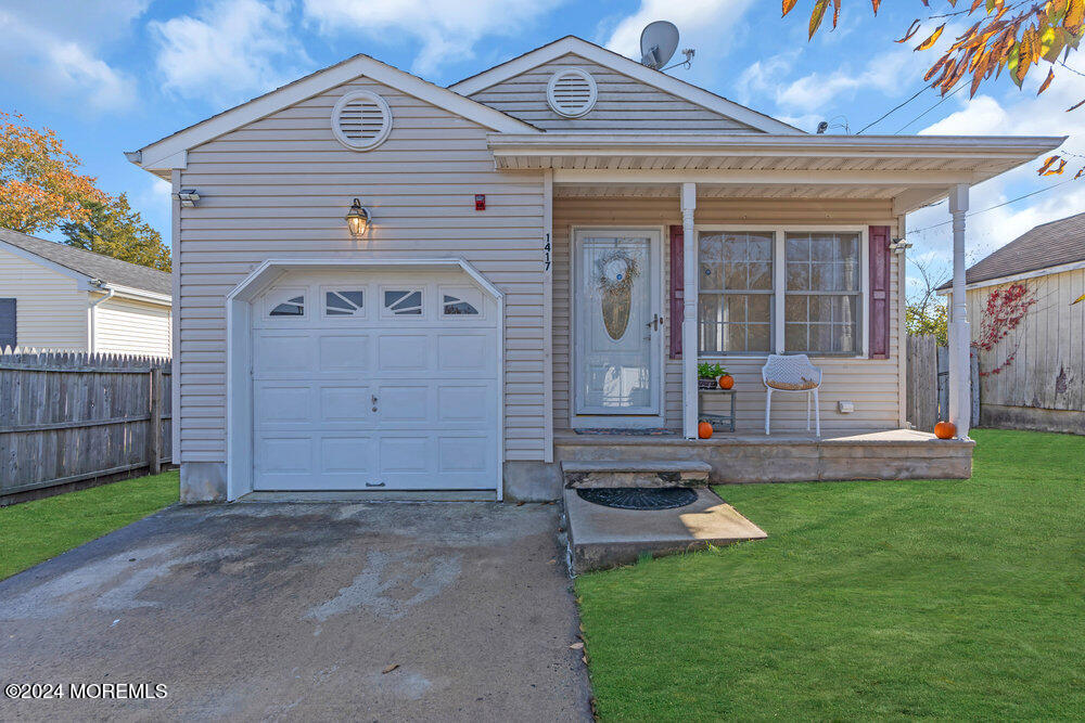 view of front of home featuring a front yard, a garage, and a porch