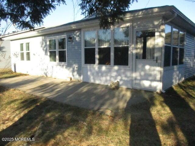 view of side of home with a patio and a lawn