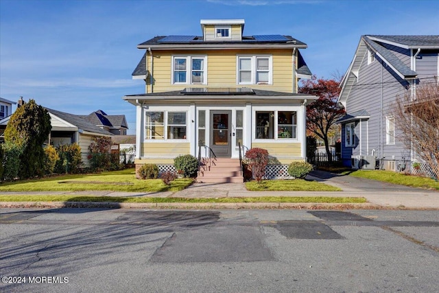 view of front of home featuring solar panels and a front lawn