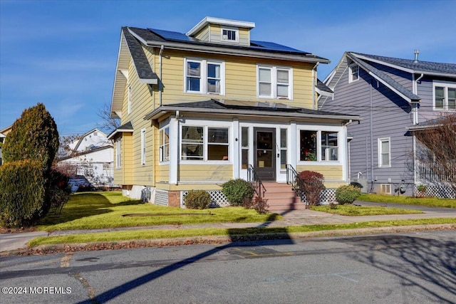 view of front facade featuring solar panels and a front lawn