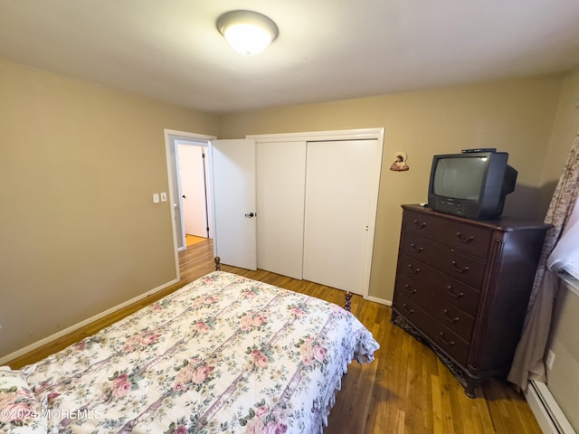 bedroom featuring a closet, light wood-type flooring, and a baseboard radiator