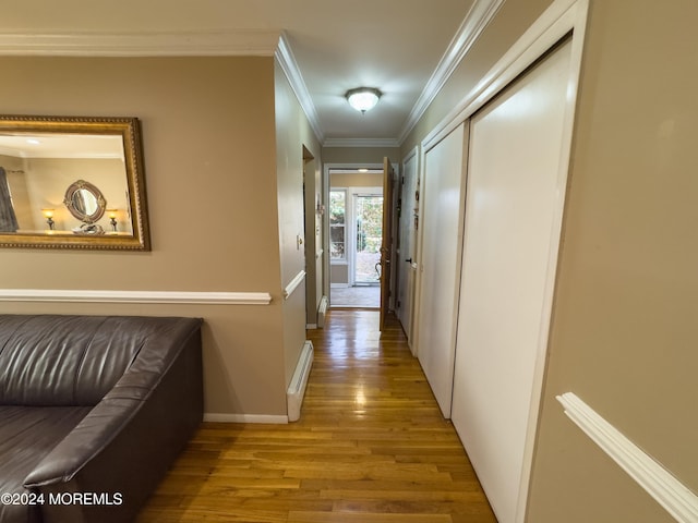 corridor featuring light wood-type flooring, a baseboard radiator, and crown molding