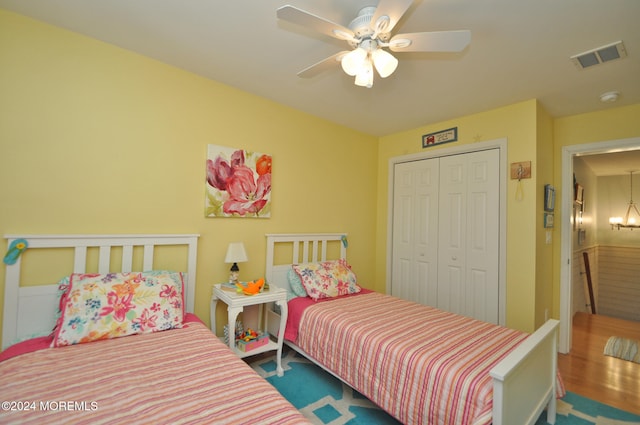 bedroom with a closet, wood-type flooring, and ceiling fan with notable chandelier