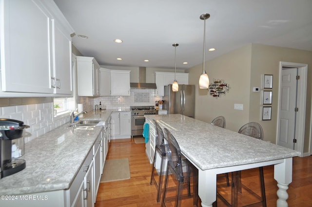 kitchen with wall chimney range hood, a center island, white cabinetry, and stainless steel appliances