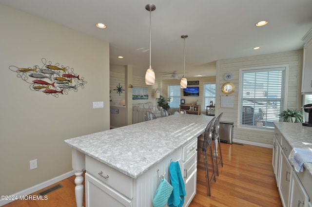 kitchen featuring white cabinetry, light hardwood / wood-style floors, a kitchen island, and hanging light fixtures