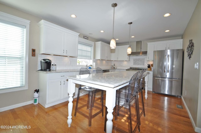 kitchen with light hardwood / wood-style flooring, stainless steel fridge, decorative light fixtures, and backsplash