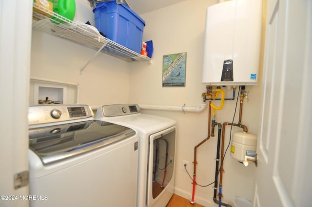 clothes washing area with independent washer and dryer, hardwood / wood-style flooring, and water heater