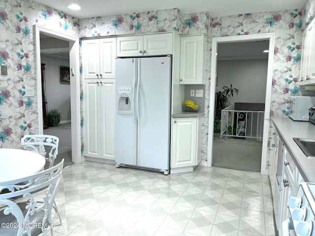 kitchen with white cabinets, white fridge with ice dispenser, and sink