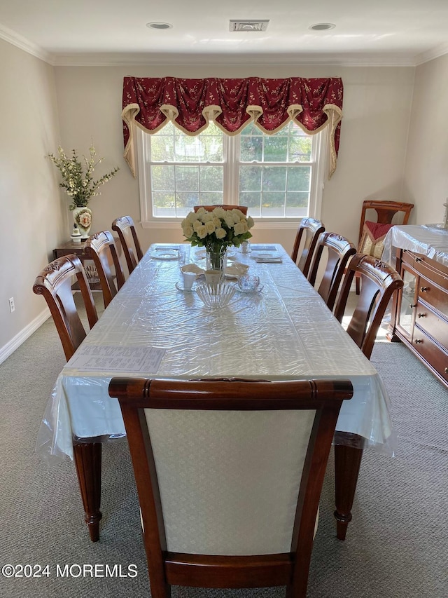 carpeted dining space featuring crown molding