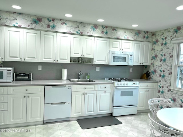 kitchen featuring white appliances, white cabinetry, and sink