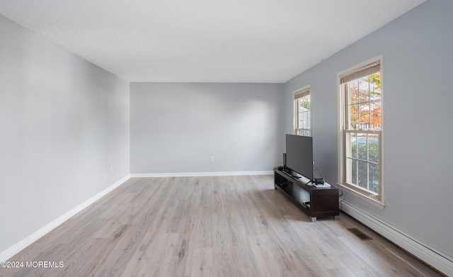 unfurnished living room with light hardwood / wood-style floors and baseboard heating