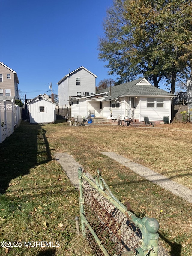 back of house with a fenced backyard, a lawn, entry steps, and an outdoor structure