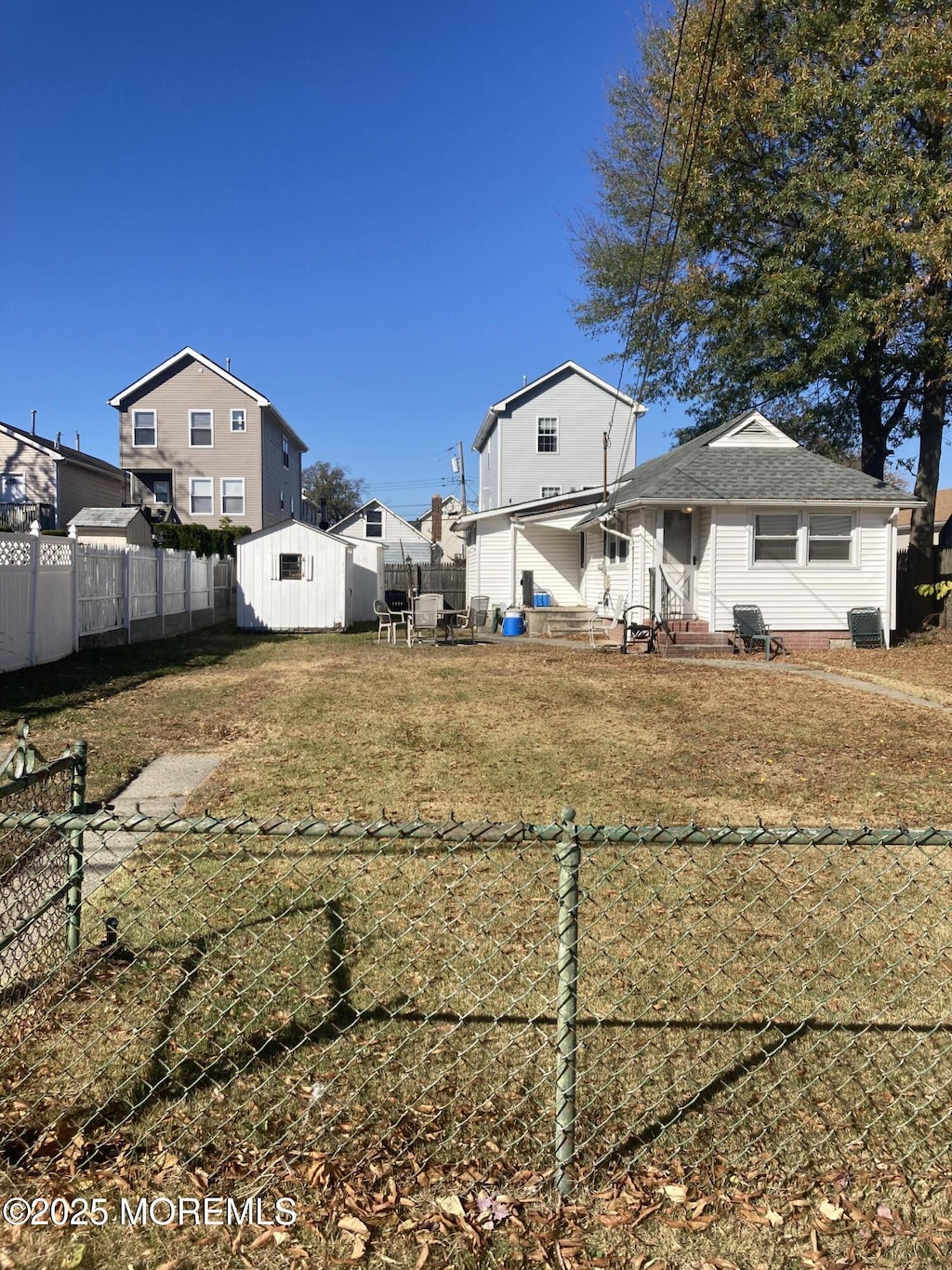 view of yard with a fenced backyard, a shed, entry steps, and an outdoor structure