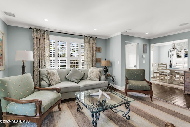 living room with crown molding, hardwood / wood-style flooring, and a chandelier